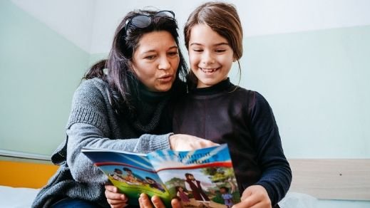 Mutter und Tochter schauen sich das Heft "Das größte Geschenk" an.