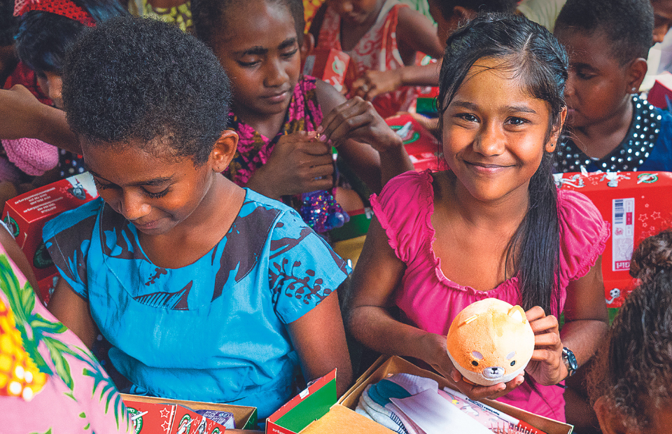 Mädchen aus Fidschi erhält Schukartongeschenk.