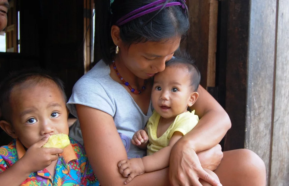 Diese Mutter und ihr Kind profitierten vom Baby-Not-Projekt Eine Mutter hat Ihr Kleinkind auf dem Schoß, neben ihr ein weiteres Kind.