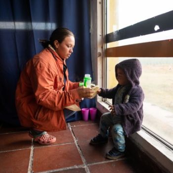 Mutter gibt Kind etwas zu essen in Notunterkunft in Kolumbien